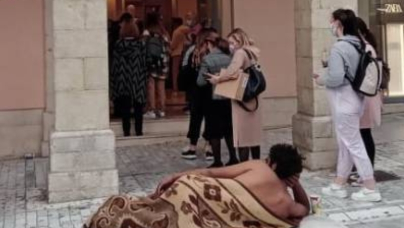Ημίγυμνος άντρας, καλυμμένος με κουβέρτα, ξάπλωσε μπροστά από εμπορικό στην Πάτρα και κοιτούσε τους πελάτες 